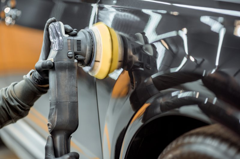 Eine Poliermaschine wird an einem schwarzen Auto zur professionellen Aufbereitung genutzt